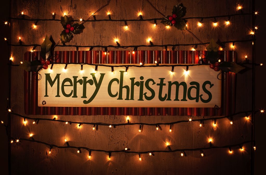 Picture of Merry Christmas banner on brown grunge door at home, happy New Year, glowing electrical garland, Christmastime house interior, congratulations postcard, holiday illumination