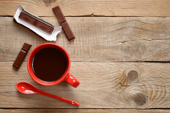 Coffee cup with chocolate on wooden background